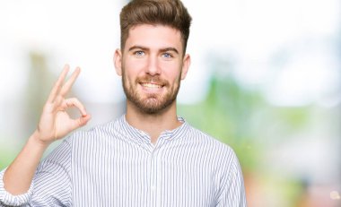 El ve parmak ile ok işareti yapıyor olumlu gülümseyen yakışıklı delikanlı. Başarılı ifade.