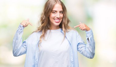 Yüzünde gülümseme ile kendinden emin görünüyorsun, kendini gururlu ve mutlu parmakları ile işaret izole arka plan üzerinde sarışın güzel genç kadın.