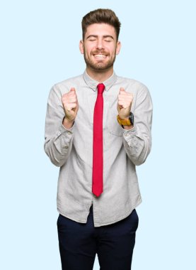 Genç yakışıklı iş adamı silah ile başarı için heyecanlı zafer kutluyor gülümseyen kaldırdı. Kazanan kavramı.