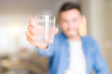 Bir bardak su evde bir gülen surat konumu olan içme ve diş gösterilen kendine güvenen bir gülümsemeyle gülümseyerek genç yakışıklı adam