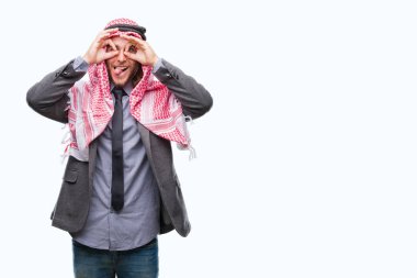 Genç yakışıklı Arap adam uzun saçlı, dilini parmaklarının arasından baktığını yapışmasını dürbün gibi ok jest yapıyor izole arka plan üzerinde keffiyeh giyiyor. Deli ifade.