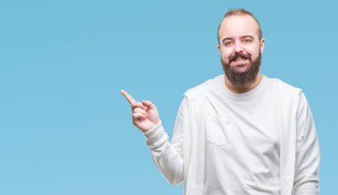 Yüzünde kocaman bir gülümseme ile izole arka plan üzerinde spor kıyafetlerle Genç beyaz hipster adam kameraya bakarak yan el ve parmak ile işaret.