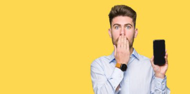Genç yakışıklı adam iş smartphone ekran kapağı ağız el ile gösterilen hata, korku, sessizlik içinde gizli kavramı korkmuş ifade için utanç ile şok