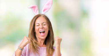 Gülümseyen ve başarı için çığlık Paskalya tavşan kulakları izole arka plan çok mutlu ve heyecanlı kaldırdı, silah ile kazanan jest yapıyor üzerinde giyen orta yaş esmer kadın. Kutlama kavramı.