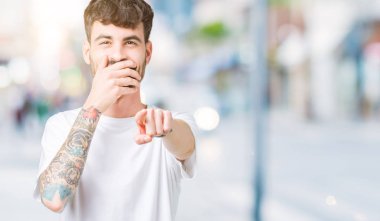 Beyaz t-shirt üzerinde izole giyen genç yakışıklı adam arka plan sizin parmak el kamerasıyla ağzına, utanç ifadesi işaret eden gülme