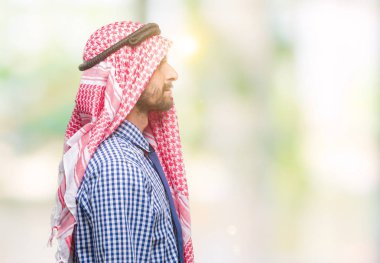 Genç yakışıklı Arap iş adamı giyen keffiyeh izole arka tarafına, seyir üzerinde dinlenmek doğal yüz emin gülümseme ile pozuyla profili.