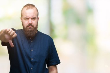 Genç beyaz hipster adam mutsuz ve kızgın ret gösterilen ve başparmak aşağı hareketi ile negatif seyir izole arka plan üzerinde. Kötü ifade.