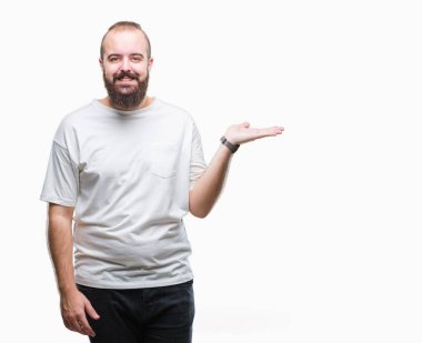 Neşeli sunulması ve kameraya bakarak avucunun ile işaret gülümseyen izole arka plan üzerinde rahat t-shirt giyen genç beyaz hipster adam.