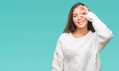 Gülümseyerek el parmakları ile mutlu yüz üzerinden seyir göz ile ok jest yapıyor izole arka plan üzerinde kış kazak giyen genç güzel Arap kadın.