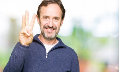 Gösterilen ve parmakları ile işaret Kazak giyen orta yaş yakışıklı adam kendinden emin ve mutlu gülümseyerek iken üçüncü.