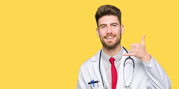 Joven Doctor Guapo Con Abrigo Médico Sonriendo Haciendo Gesto Telefónico — Foto de Stock