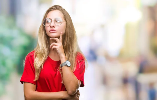 年轻漂亮的金发女人戴着眼镜 在孤立的背景下 手放在下巴思考问题 沉思的表情 微笑与周到的脸 怀疑概念 — 图库照片