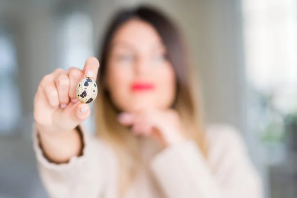 Young Beautiful Woman Holding Fresh Quail Egg Home Serious Face — Stock Photo, Image