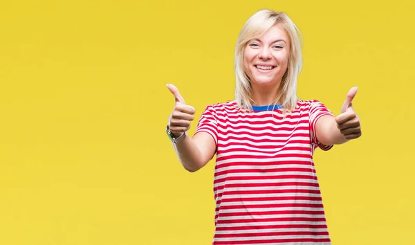 Young beautiful blonde woman over isolated background success sign doing positive gesture with hand, thumbs up smiling and happy. Looking at the camera with cheerful expression, winner gesture.