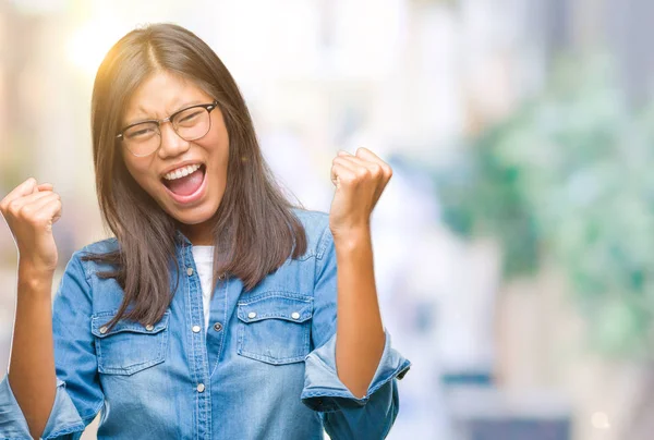 若いアジア女性は笑みを浮かべて 成功のために叫んで非常に幸せと興奮の腕を上げ 勝者のジェスチャを行う分離の背景にメガネを着用します お祝いのコンセプト — ストック写真