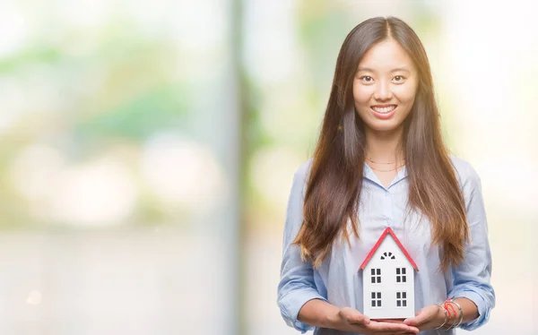 Young asian woman real state agent holding house isolated background with a happy face standing and smiling with a confident smile showing teeth