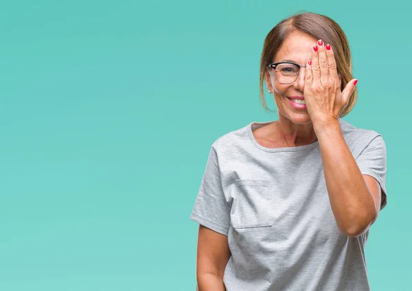 中年年配のヒスパニック系女性顔と驚きの感情に自信を持って笑顔で手で片目を覆う孤立の背景に眼鏡 — ストック写真