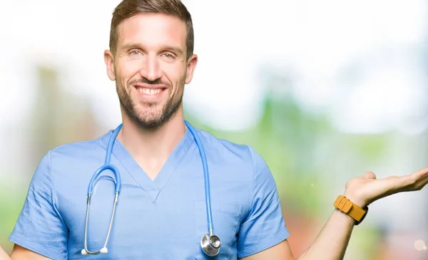 英俊的医生穿医疗制服在孤立的背景微笑显示双手张开手掌 呈现和广告比较和平衡 — 图库照片
