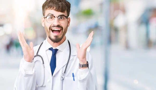 年轻的医生人穿医院外套在孤立的背景庆祝疯狂和惊奇为成功与胳膊举起和睁大眼睛尖叫兴奋 优胜者概念 — 图库照片