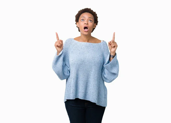 年轻美丽的非洲裔美国妇女穿着一件毛衣在孤立的背景惊讶和惊讶地抬头 用手指指指点点 举起双臂 — 图库照片