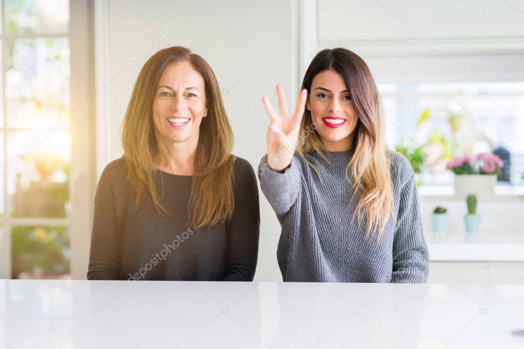 Beautiful family of mother and daughter together at home showing and pointing up with fingers number three while smiling confident and happy.
