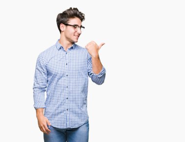 Seyir ve başparmak yanında yukarıyı mutlu yüz ile gülümseyen izole arka plan üzerinde gözlük takan genç yakışıklı adam.