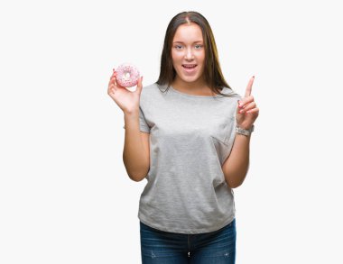 Genç kafkas kadın yemek tatlı çörek üzerinde arka plan ile bir fikir ya da gülen yüz, bir numara ile parmak işaret soru sürpriz izole