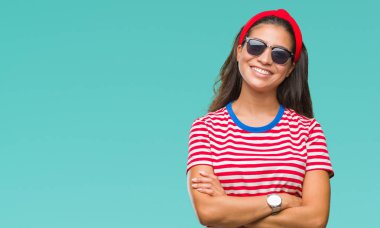 Genç güzel Arap kadın üzerinde güneş gözlüğü takıyor mutlu yüz ile gülümseyerek kameraya seyir silah geçti arka plan izole. Olumlu bir kişi.