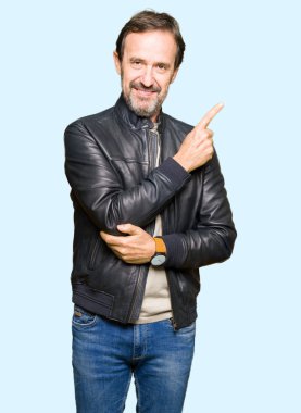 Siyah deri giyen orta yaş yakışıklı adam reklam, ciddi ve sakin yüz gösterilen yan el parmak ile işaret ceket