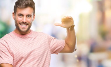 Yakışıklı delikanlı ile büyük ve büyük boy işaret, ölçü birimi sembol gösteren el eller izole arka plan üzerinde. Kameraya bakarak gülümsüyordu. Ölçüm kavramı.