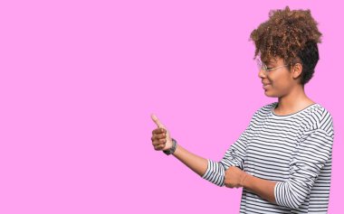 Yanına bir jest yapıyorsun gülümseyen izole arka plan gurur, seyir üzerinde gözlük güzel genç Afro-Amerikan kadın yaşasın