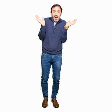 Bir kazak clueless ve şaşkın ifadeyle kollar ve eller kaldırdı giyen orta yaş yakışıklı adam. Şüphe kavramı.