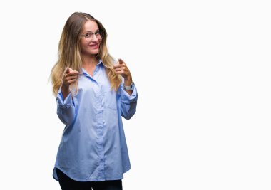 Fotoğraf makinesi ile mutlu ve komik yüz için parmakları işaret izole arka plan üzerinde gözlük takan genç güzel sarışın iş kadını. İyi enerji ve vibes.