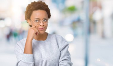 Emin çapraz kollar ve çeneme kaldırdı el ile gülümseme ile kameraya bakarak izole arka plan üzerinde gözlük takan genç güzel Afrikalı-Amerikalı kadın. Pozitif düşünce.