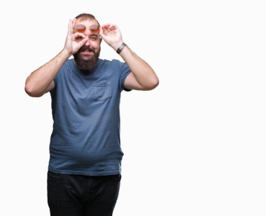 Genç beyaz hipster adam gülümsüyor, parmakları ile mutlu yüz üzerinden seyir göz el ile ok jest yapıyor izole arka plan üzerinde güneş gözlüğü takıyor.