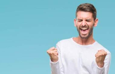 Soyutlanmış, mutlu ve heyecanlı genç bir adam kollarını kaldırmış, gülümseyen ve başarı için çığlık atan kazanan bir jest yapıyor. Kutlama konsepti.