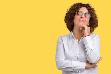 Güzel orta ager üst düzey iş kadını üzerinde güneş gözlüğü takıyor arka plan çene düşünme hakkında soru, dalgın ifade üzerine el ile izole. Düşünceli yüzüyle gülümsüyor. Şüphe kavramı.