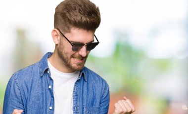 Gülümseyen ve başarı için çığlık denim ceket çok mutlu ve heyecanlı kaldırdı, silah ile kazanan jest yapıyor yakışıklı zarif delikanlı. Kutlama kavramı.