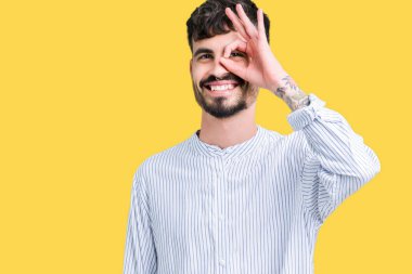 Genç yakışıklı iş adamı gülümseyen, parmakları ile mutlu yüz üzerinden seyir göz el ile ok jest yapıyor izole arka plan üzerinde.