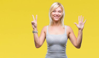Genç güzel sarışın kadın gösterilen ve parmakları ile işaret izole arka plan yüzünden kendinden emin ve mutlu gülümseyerek süre yedi numara.