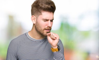 Soğuk veya bronşit için çizgili süveter duygu hasta ve öksürük semptom olarak takmış yakışıklı delikanlı. Sağlık kavramı.