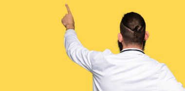 Sakal tıbbi giyen ile genç sarışın doktor erkek ceket geriye doğru arkasında parmak eliyle işaret Posing
