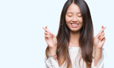 Umut ve gözleri kapalı geçiş parmaklarıyla gülümseyen izole arka plan üzerinde Genç Asyalı kadın. Şans ve batıl kavramı.