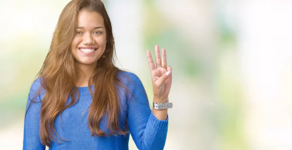 年轻美丽的黑发女人穿着蓝色毛衣在孤立的背景显示和手指第三 而微笑着自信和快乐 — 图库照片