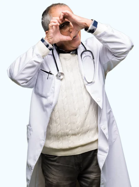 英俊的资深医生穿医疗外套做心脏形状用手和手指微笑看通过标志 — 图库照片