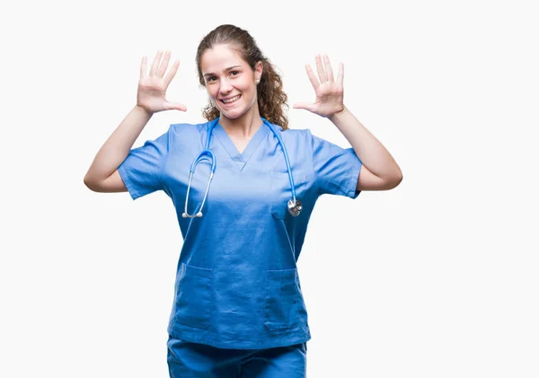 年轻的黑发医生女孩穿着护士或外科医生制服在孤立的背景显示和手指指向数字十 而微笑自信和快乐 — 图库照片