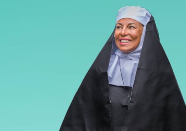 Orta yaş üst düzey Hıristiyan Katolik Rahibe kadın uzak tarafına yüzünde, doğal ifade gülümseme ile seyir izole arka plan yüzünden. Kendine güvenen gülüyor.