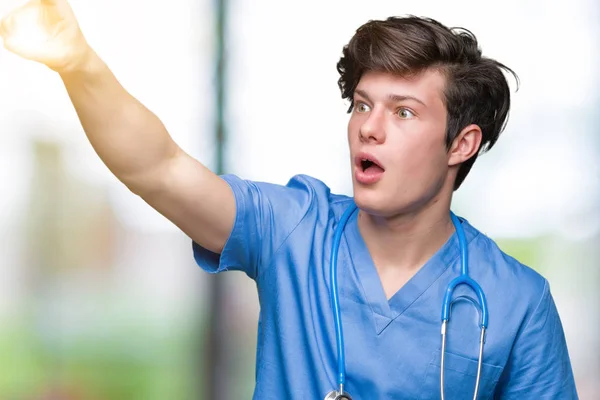 年轻的医生穿着医疗制服在孤立的背景指向用手指惊讶提前 张开嘴惊讶的表情 在前面的东西 — 图库照片