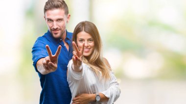 Genç çift kamera zafer işareti yapıyor parmak gösteren seyir gülümseyen izole arka plan üzerinde aşık. İki numaralı.