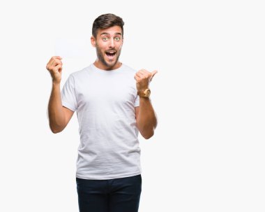 İşaret ve başparmak kadar mutlu yüz gülümseyen tarafı ile gösteren izole arka plan üzerinde boş kartı tutan genç yakışıklı adam